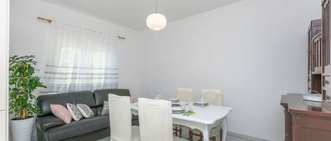 Uma área de refeições com uma mesa branca, quatro cadeiras e um lustre.