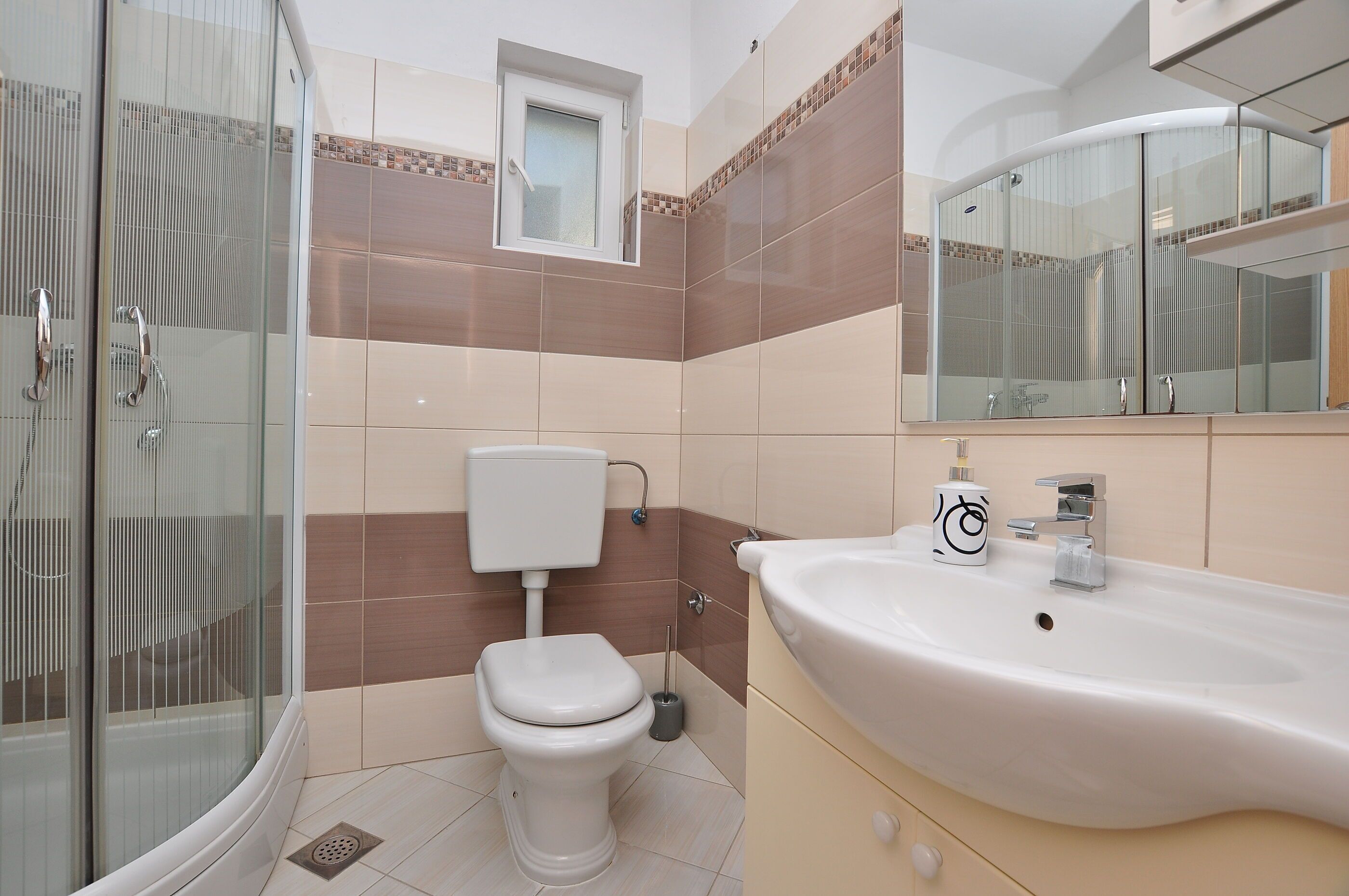 Une salle de bain moderne avec une douche à parois de verre, des toilettes et un lavabo avec un miroir au-dessus.