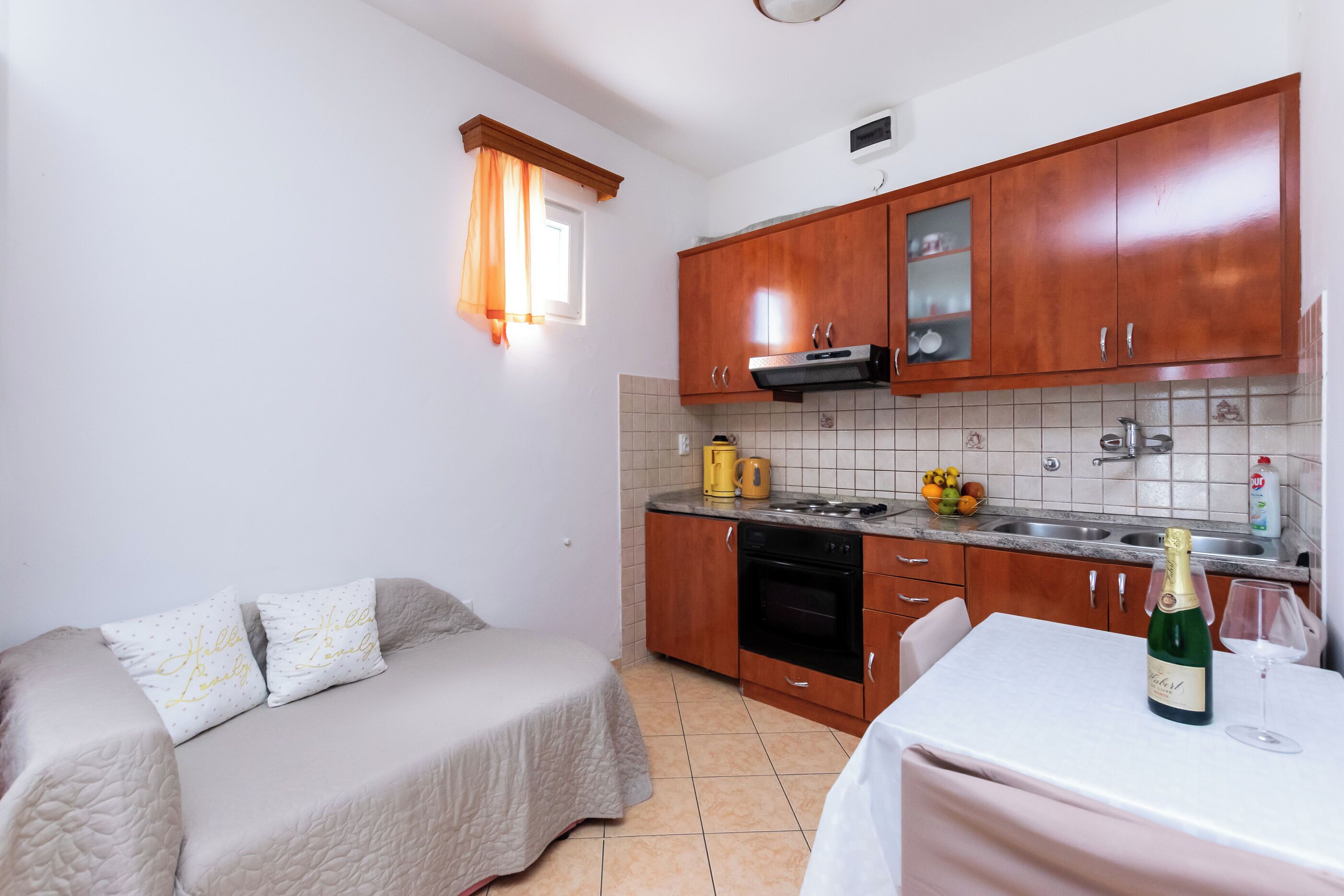 A compact kitchen with wooden cabinets, a built-in oven, and a dining area with a table set for two.