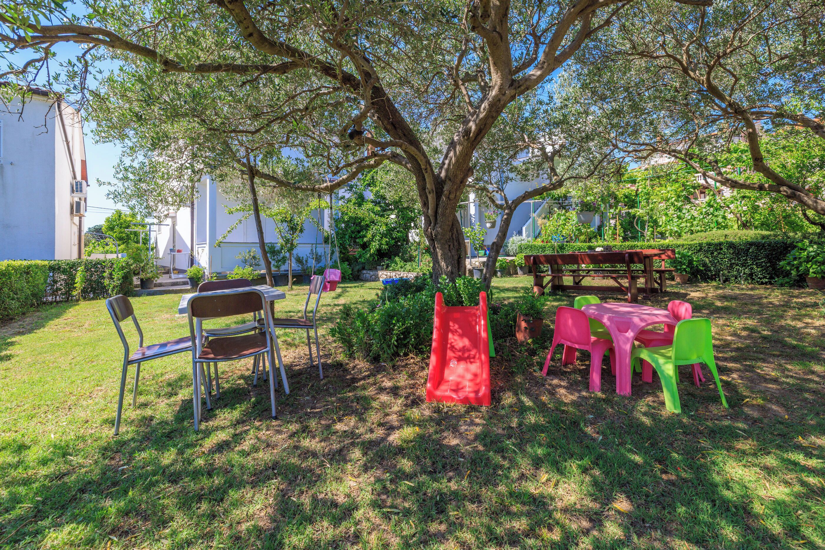 Un jardín con una mesa de picnic, sillas y un tobogán.