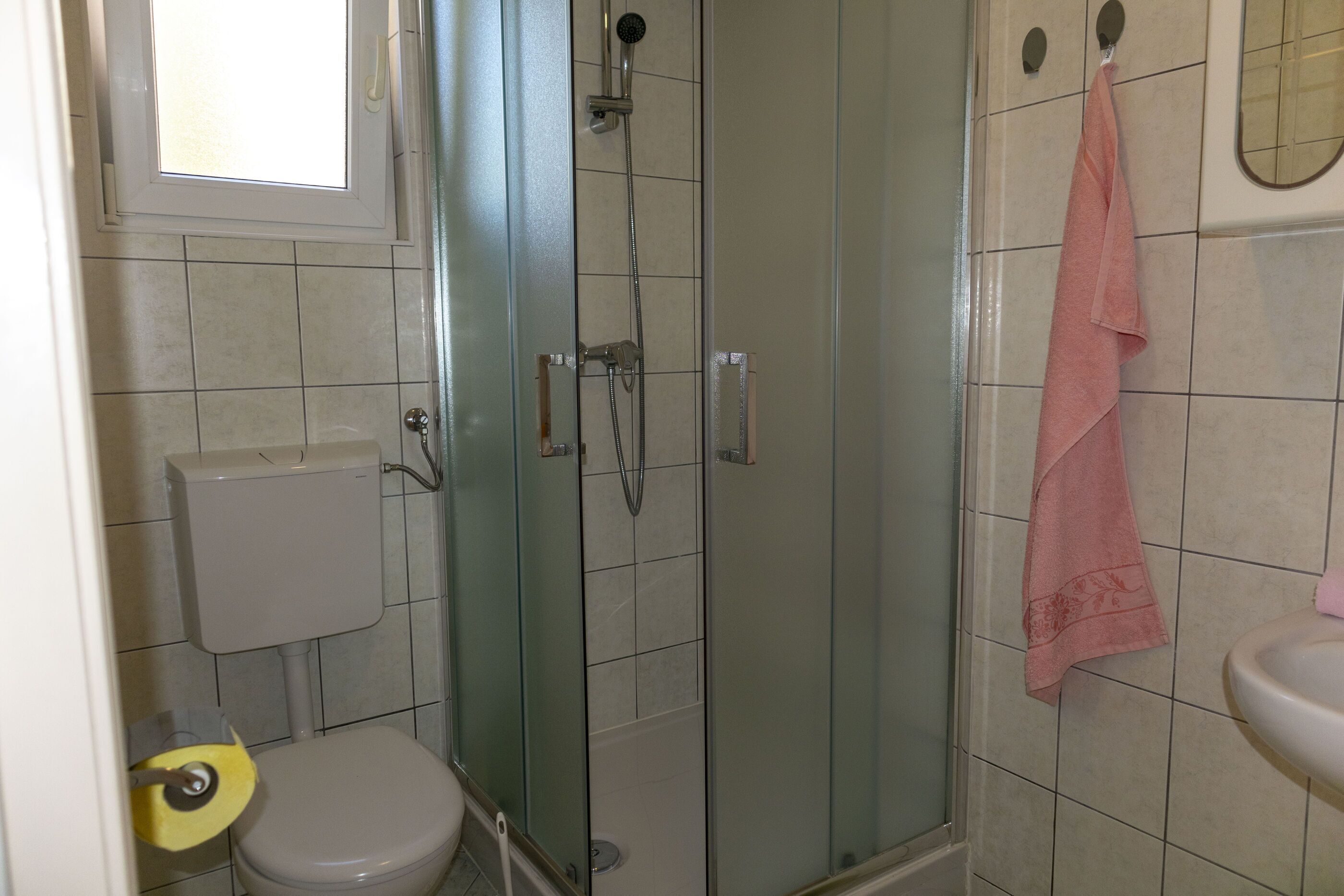 A bathroom with a glass-enclosed shower, a toilet, and a sink.