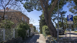 A pathway leading to a parking area with a view of the sea. - Apartments Ante (Makarska)