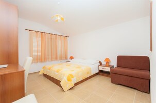 A bedroom with a bed, a desk, a chair, a nightstand, and a sofa.