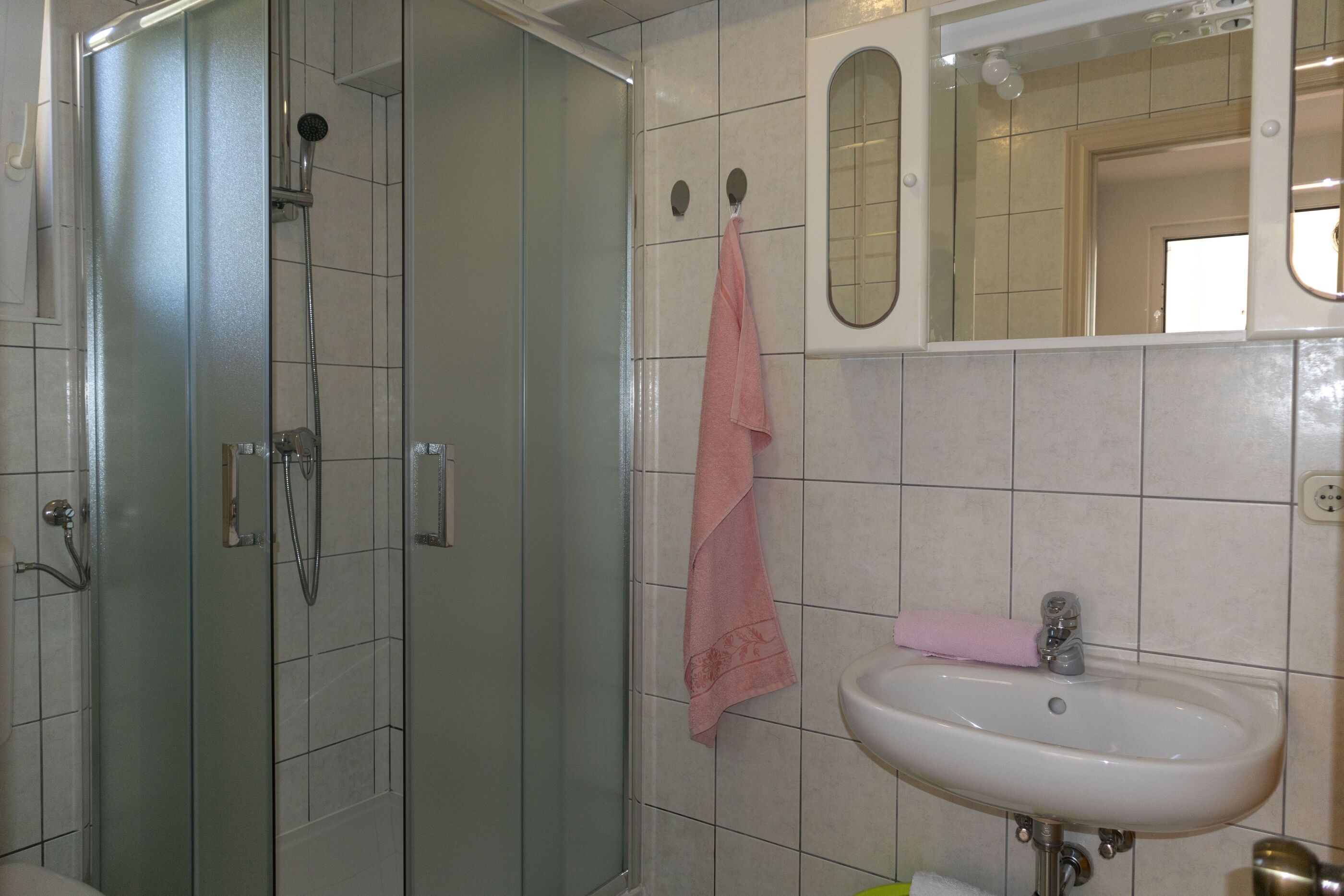 Un baño con ducha de vidrio, lavabo y espejo.