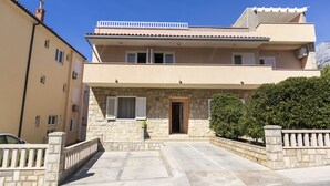 A two-story building with a stone facade, a balcony on the upper floor, and a small entrance door. - Apartments Ante (Makarska)