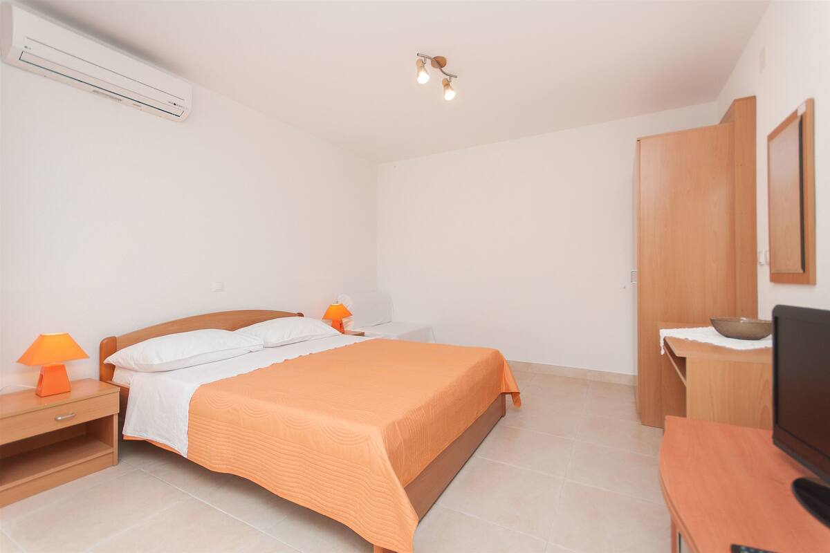 A bedroom with a bed, bedside tables, a TV, and a wardrobe.