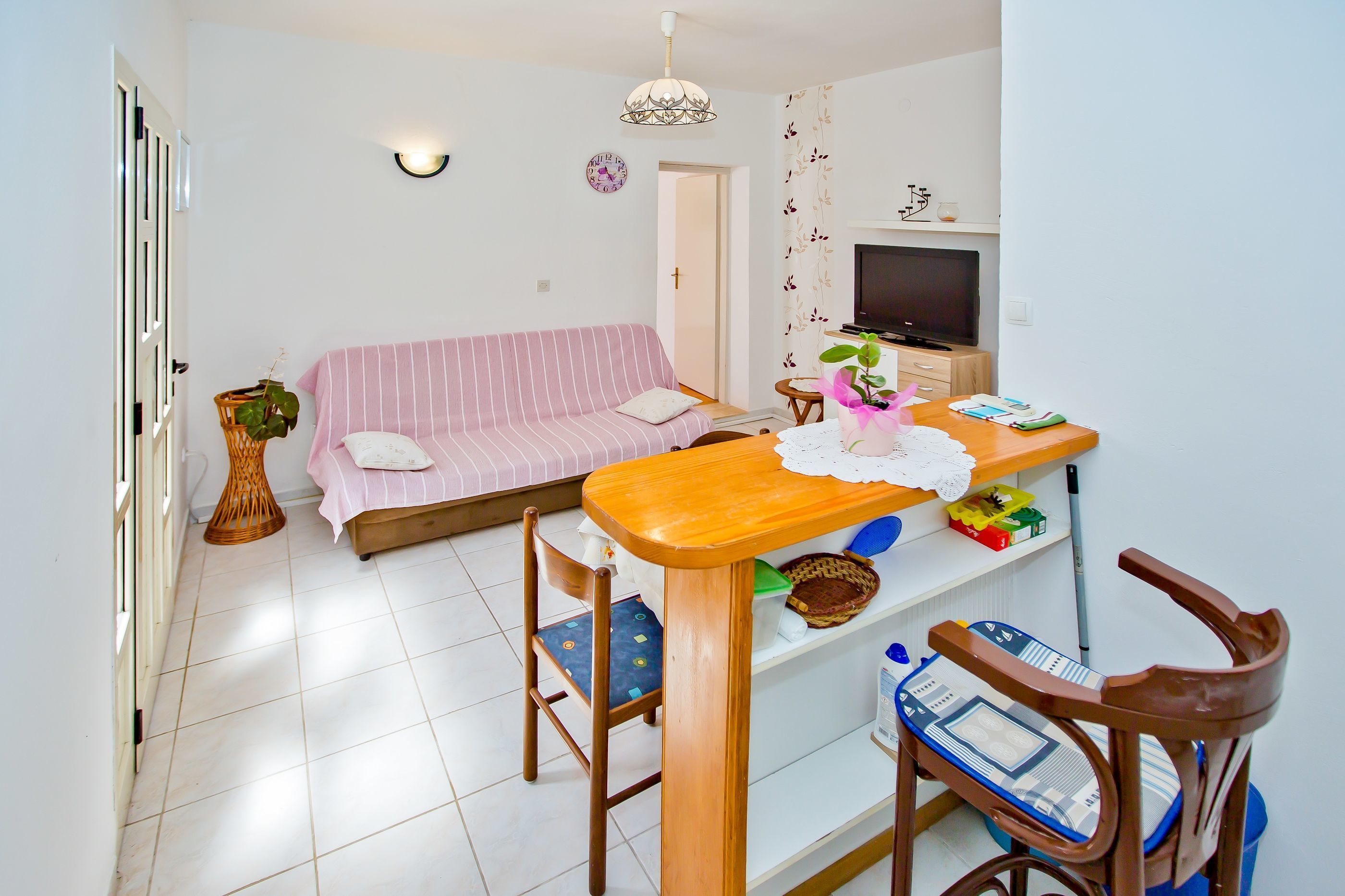 Un salon avec un canapé, une table en bois, un téléviseur et un fauteuil.