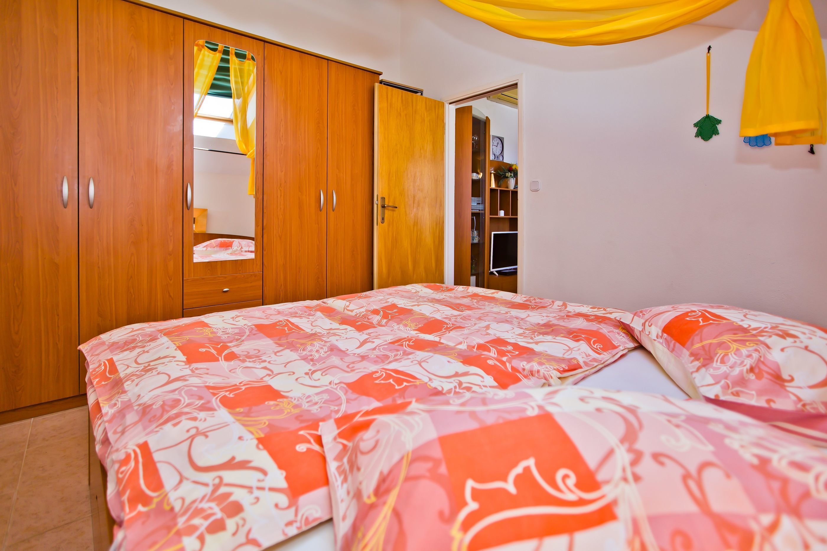 Un dormitorio con cama, armario de madera y espejo.