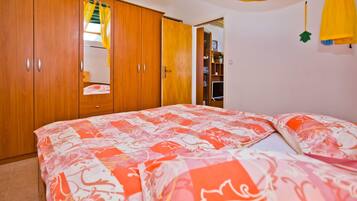 Un dormitorio con cama, armario de madera y espejo.