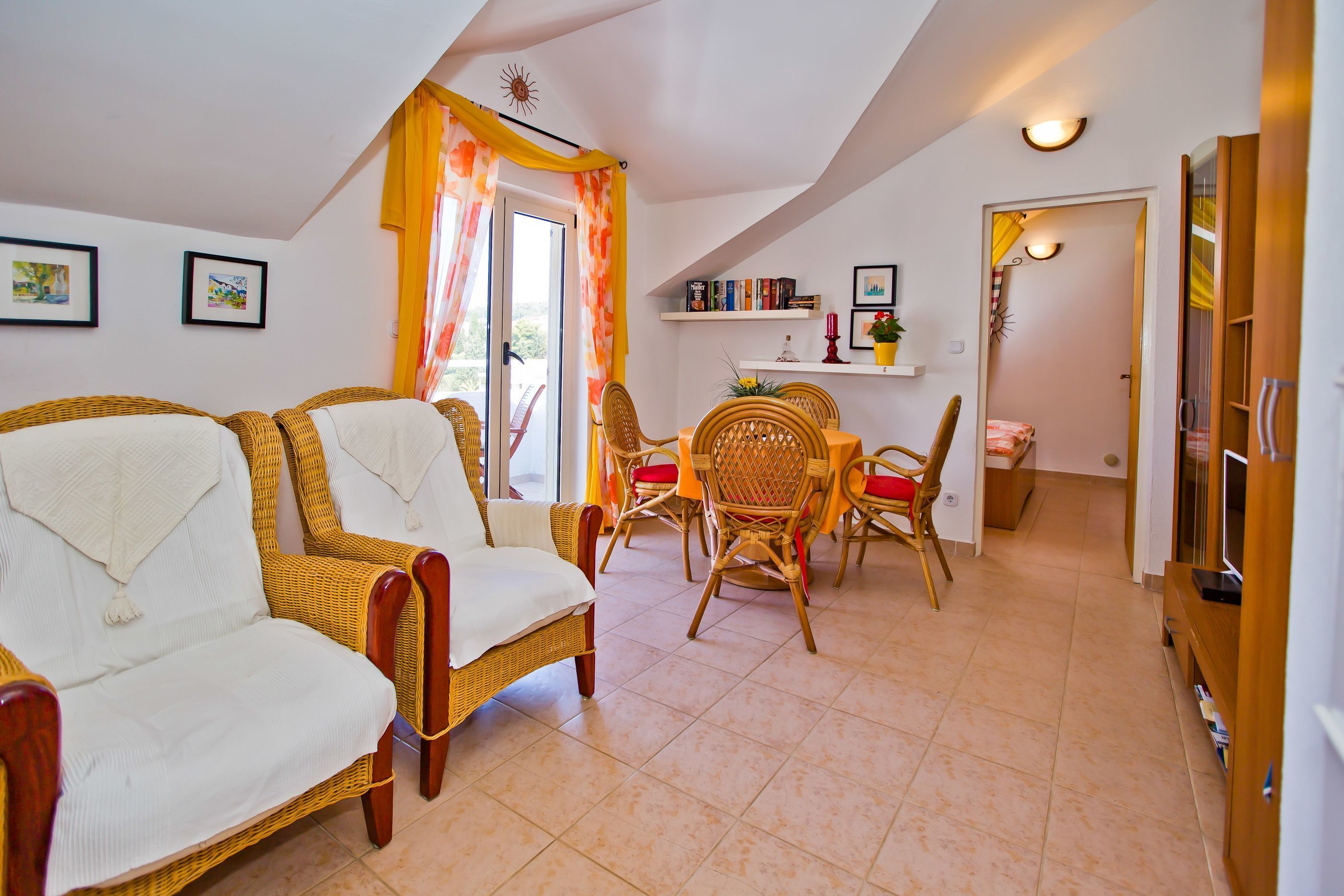 Una sala de estar acogedora con muebles de mimbre, un comedor y una estantería.
