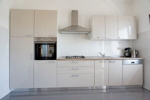 A modern kitchen with white cabinetry, a built-in oven, a gas stove, and a coffee maker. - Apartment Summer Day (Vodice)