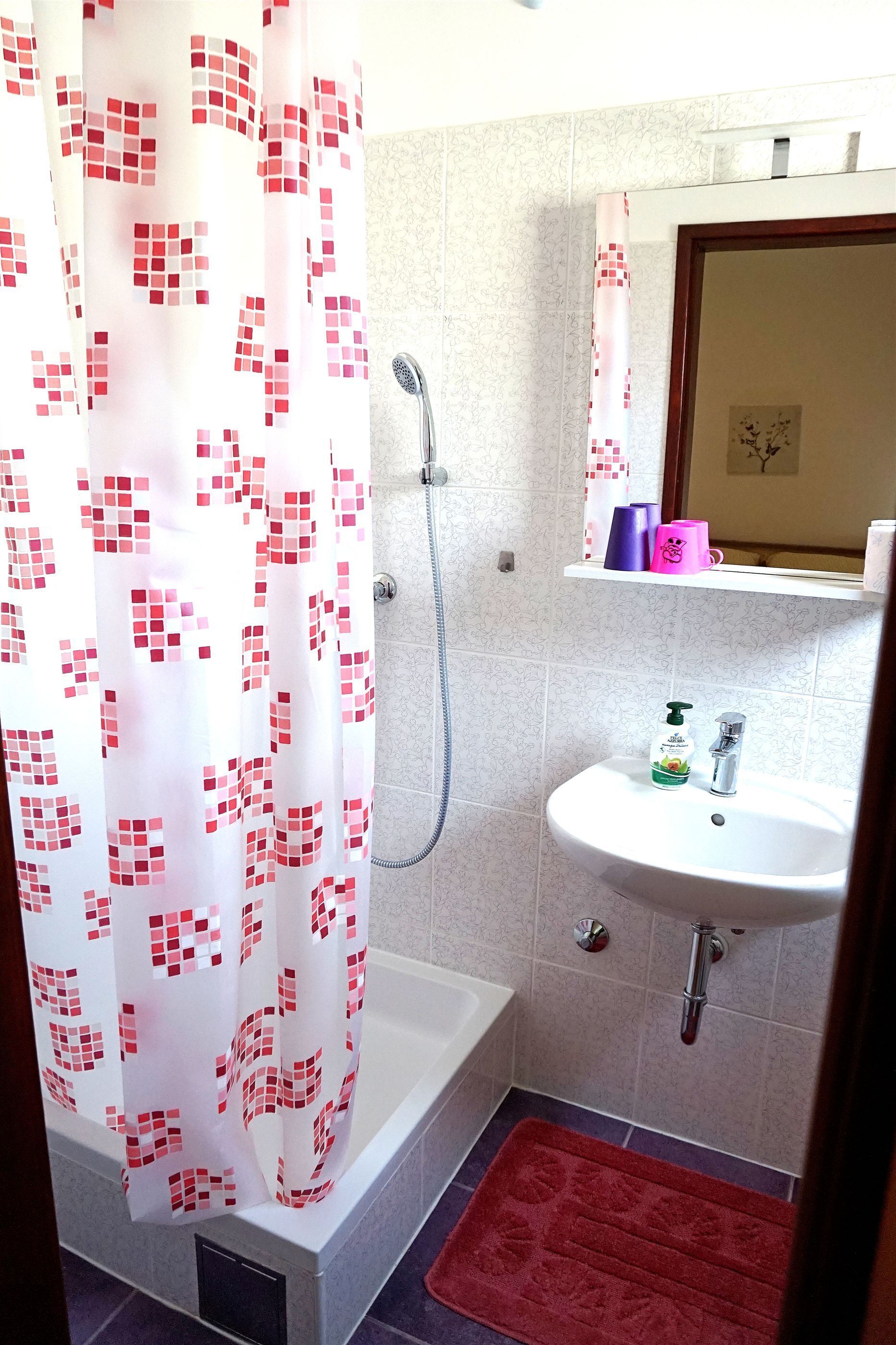 A bathroom with a shower curtain, a sink, and a mirror.