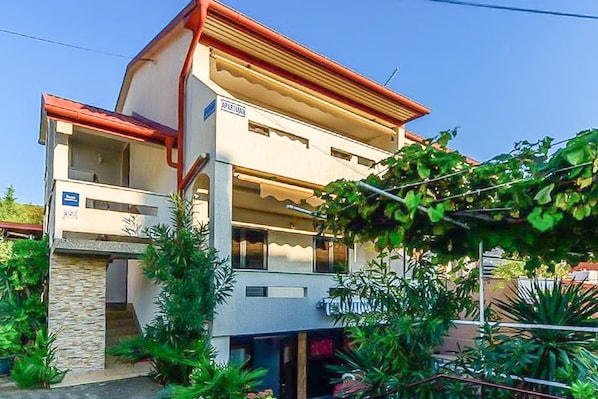 A two-story building with a balcony, a stone facade, and a sign indicating it is an apartment.