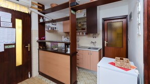 A compact kitchen with wooden cabinets, a built-in sink, and a small refrigerator. - Apartments Branka (Punat)