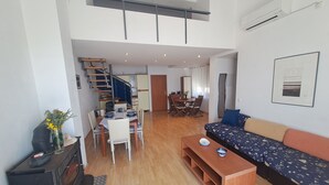 Amplia sala de estar con sofá, mesa de comedor y una escalera que conduce a un nivel superior.