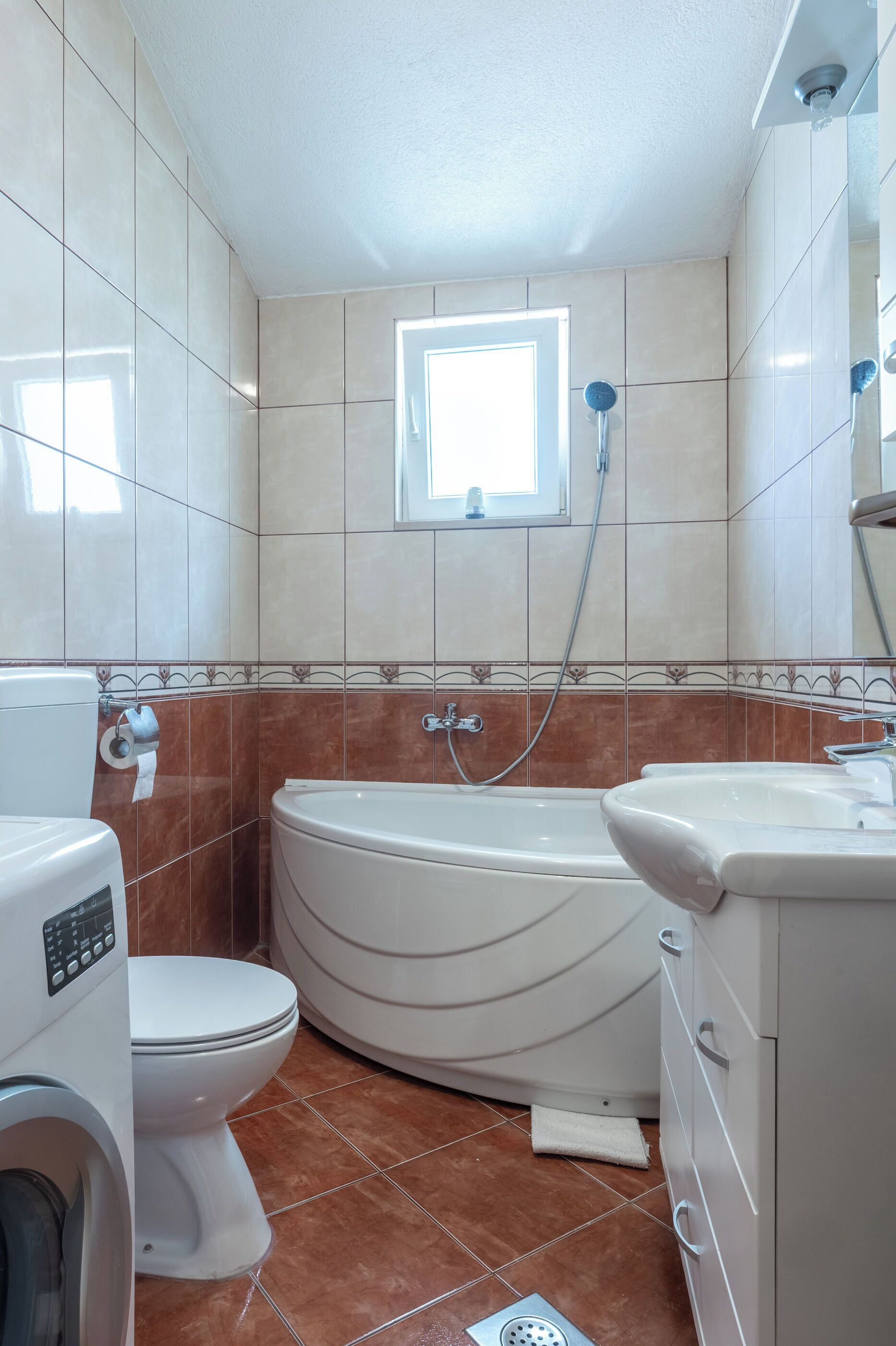 Ein Badezimmer mit Toilette, Waschmaschine, Badewanne und Waschbecken.