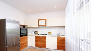 A modern kitchen with a stainless steel refrigerator, wooden cabinets, and a built-in oven. - Apartment Anica (Trogir)