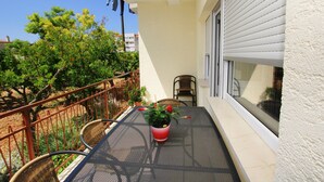 A balcony with a metal table, a potted plant, and a chair. - Apartment Anica (Trogir)