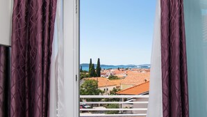 A balcony with a view of a town, including buildings and trees. - Apartments Cace (Brodarica)