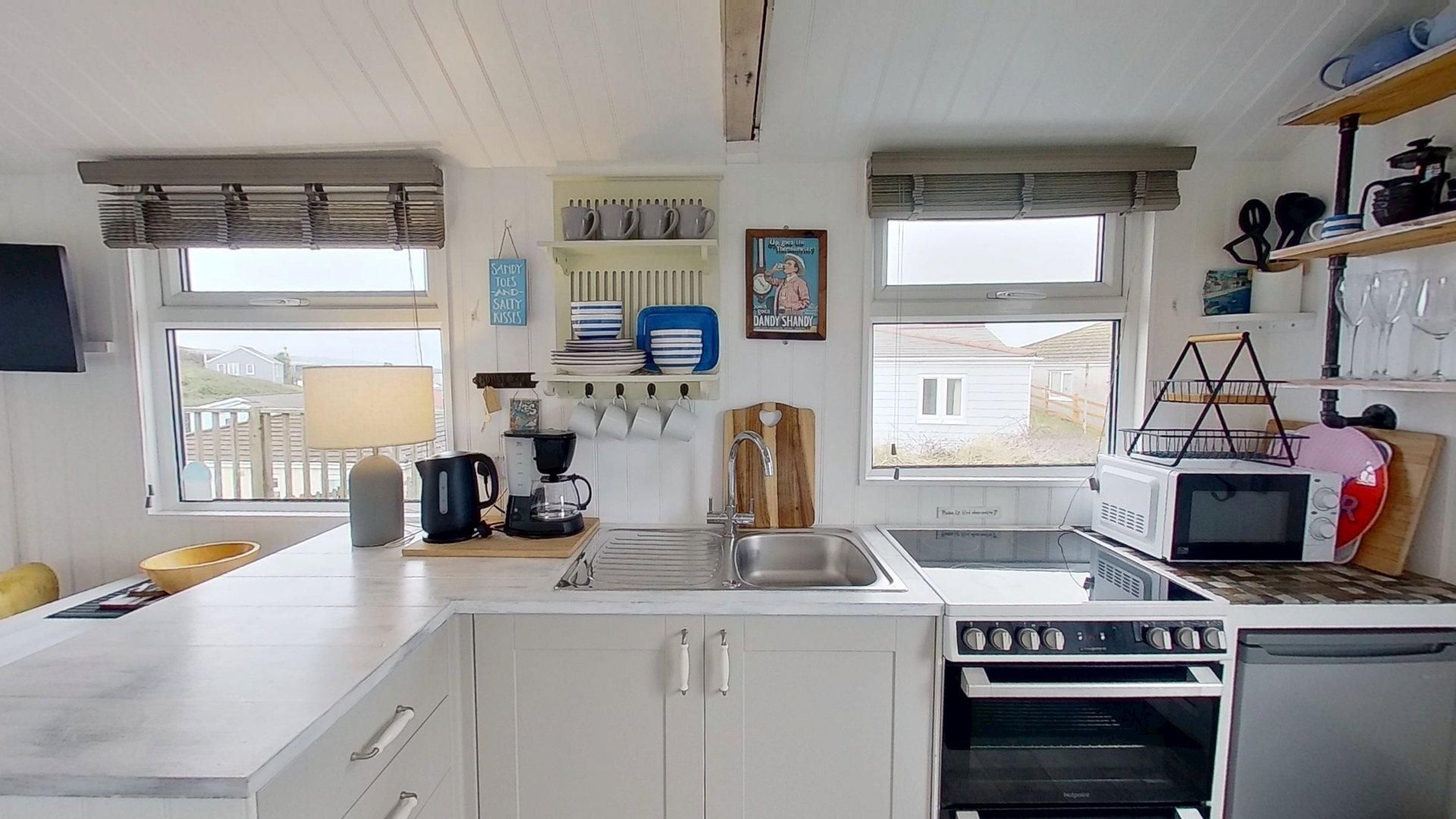 A compact kitchen with white cabinets, a sink, a coffee maker, a microwave, and a small oven.