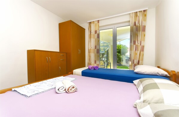A hotel room with a bed, a wooden wardrobe, and a window with curtains. - Apartment Sunny Terrace (Vodice)