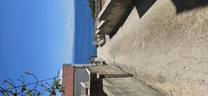 A coastal hotel with a view of the sea, a concrete wall, and a building with a tiled roof.