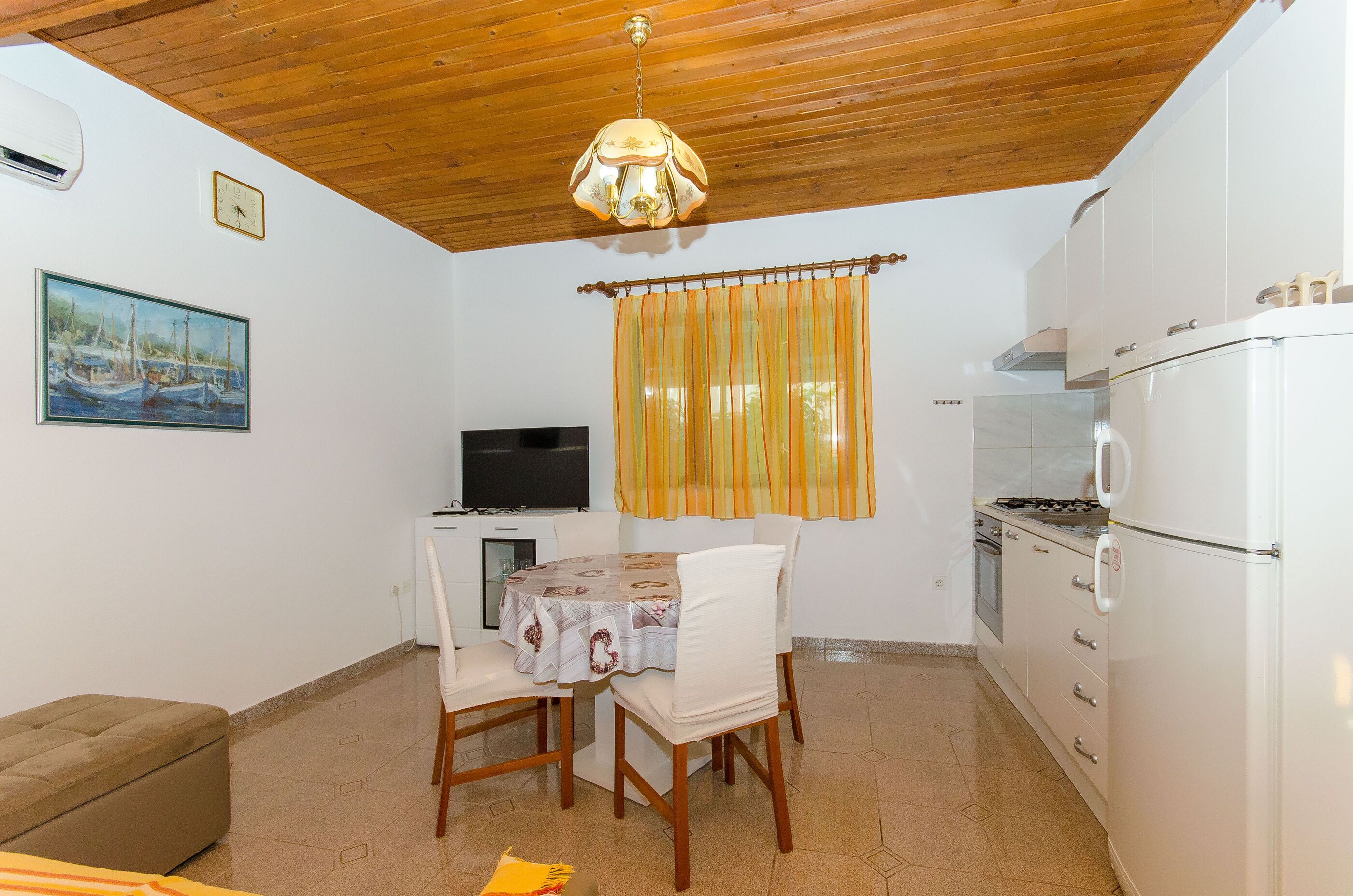 Una cocina compacta con comedor, televisor y un cuadro en la pared.