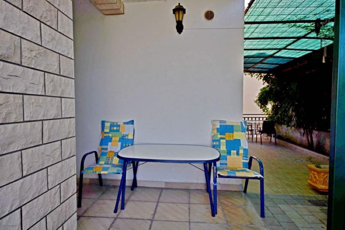 Une terrasse avec une table ronde et deux chaises, un mur en briques et un toit en verre.