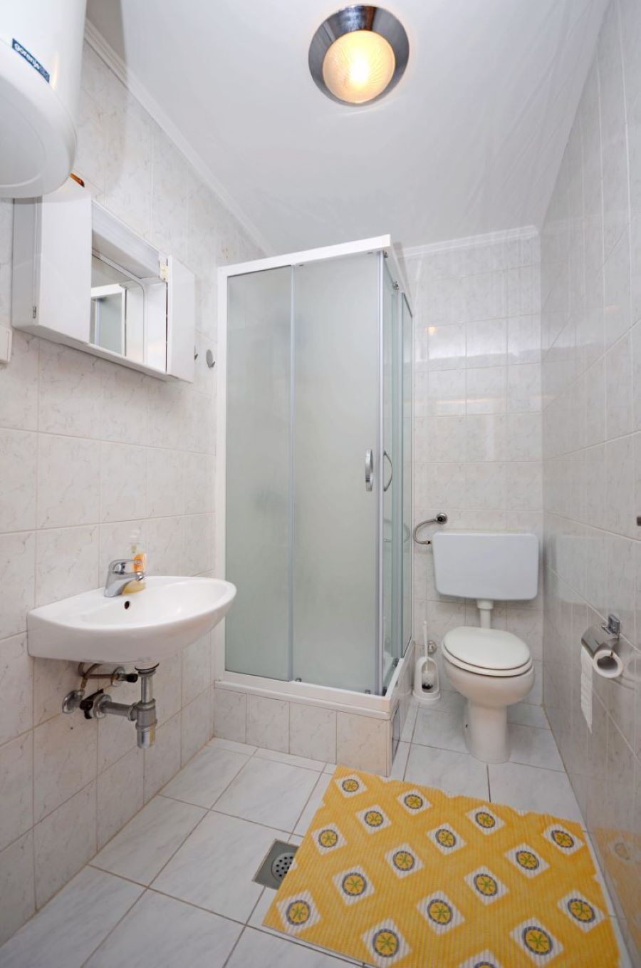 Une salle de bain avec une douche à parois de verre, un lavabo blanc et des toilettes.