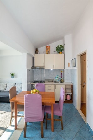 A compact kitchen with a dining table and chairs, a sofa, and a small kitchen island.