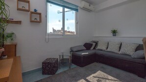 Una sala moderna con un sofá modular, una mesita auxiliar pequeña, una mesa de centro de vidrio y una planta en maceta.