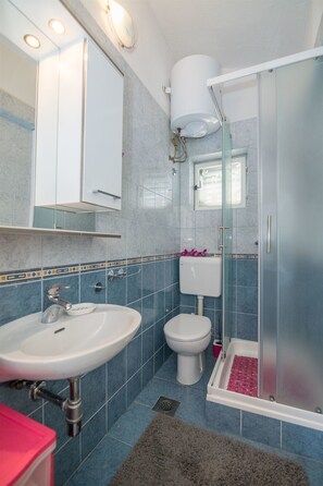 A bathroom with a sink, toilet, and glass shower enclosure. - Apartments Tolj (Igrane)
