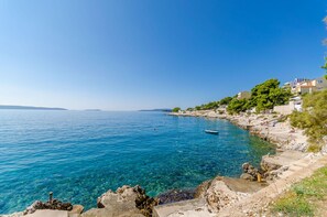 A coastal town with clear blue sea, rocky shoreline, and buildings along the coast.
