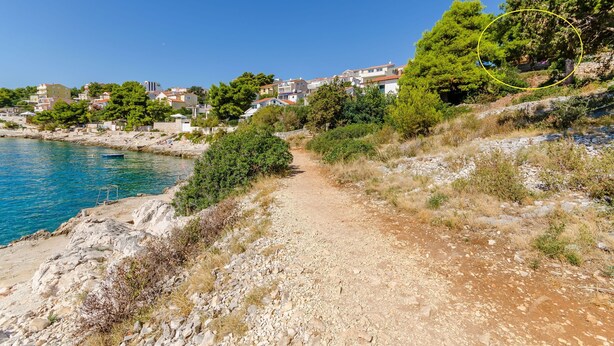 A coastal path leading to a hillside with houses, a clear blue sea, and rocky terrain. - Apartment Natasa (Okrug Gornji)
