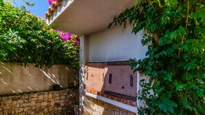 A stone-walled outdoor area with a built-in grill and lush greenery. - Apartment Natasa (Okrug Gornji)