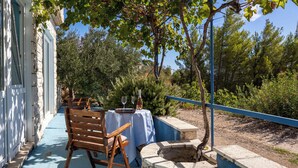 Un patio al aire libre con un hogar de piedra, sillas de madera y una mesa lista para comer.