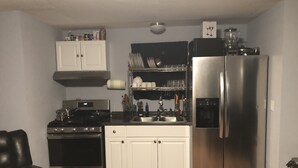 A compact kitchen with white cabinets, a stainless steel refrigerator, a stove, and a sink. - Fully private bunkhouse with all amenities. (Ashford)
