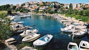 Un port de plaisance où sont amarrés plusieurs bateaux, entouré d’un quartier résidentiel vallonné.