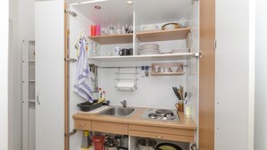 A compact kitchen with a sink, stove, and various utensils. - Apartment Maslina (Vodice)