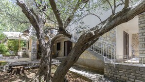 A stone building with a staircase and a tree in the foreground. - Apartment Maslina (Vodice)
