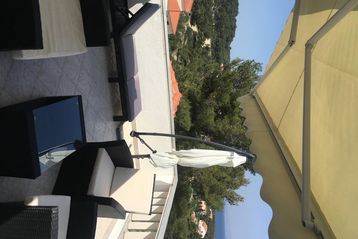 A view of a covered outdoor area with a white umbrella, a black table, and a beige canopy.