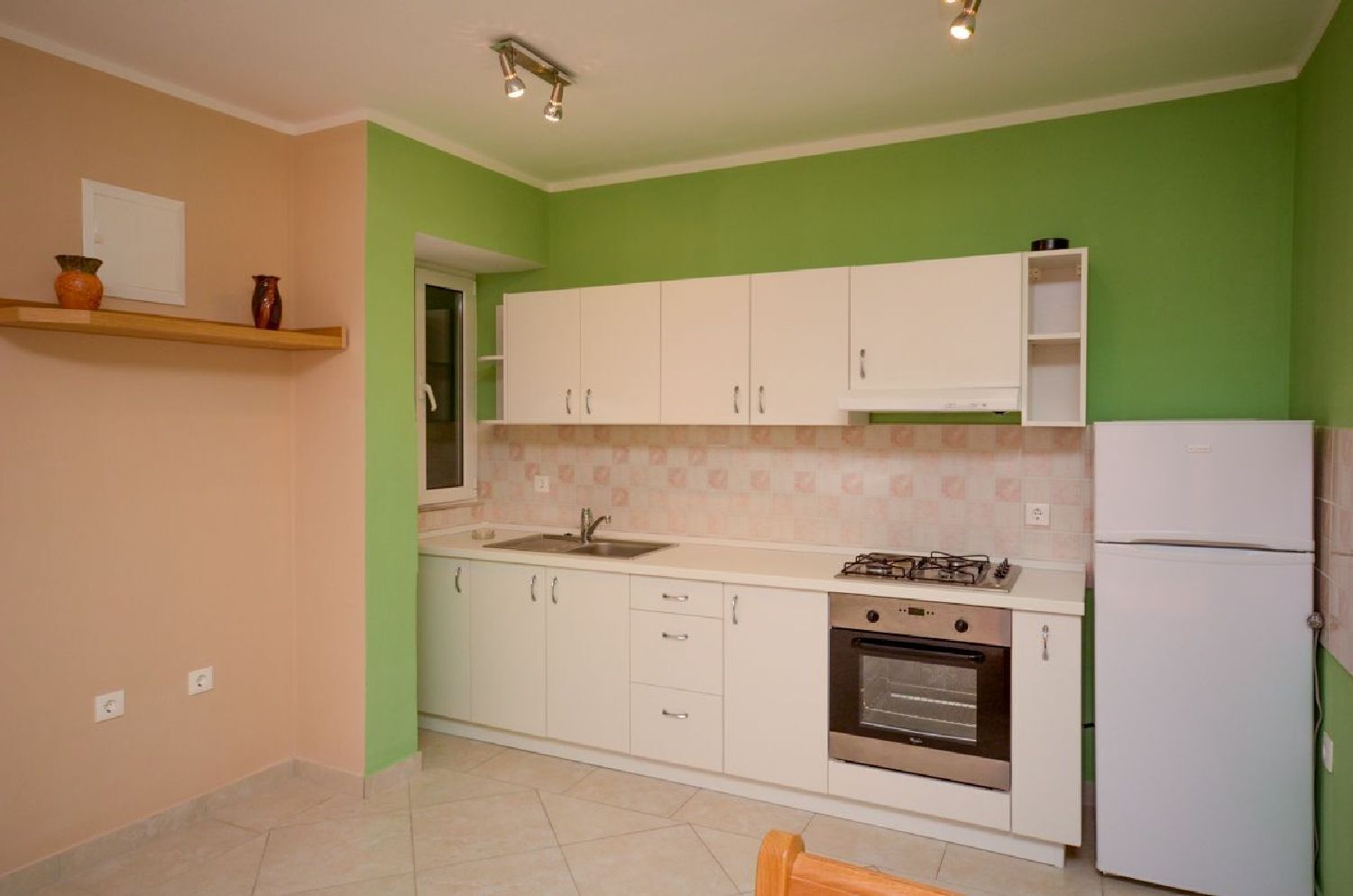 A kitchen with white cabinets, a gas stove, an oven, and a refrigerator.