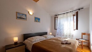 A bedroom with a bed, bedside tables, a chair, and curtains. - House The Bay (Gdinj)