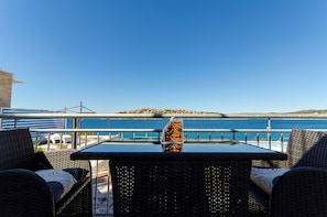 Una mesa y sillas en un balcón con vista a un cuerpo de agua y una isla distante.