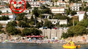 A coastal town with a beach, stone buildings, and a yellow inflatable boat on the water. - Apartment Marinera (Senj)