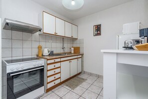 A compact kitchen with a stove, oven, and a coffee maker. - Apartment Marinera (Senj)