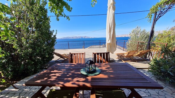 A wooden deck with a table and chairs, overlooking a beach and the sea. - Apartment Marinera (Senj)