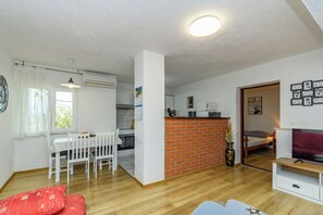 Een compacte woonruimte met een eethoek, keuken en een televisie in de woonkamer.