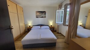 A bedroom with a bed, bedside tables, a nightstand, a window, and a mirror. - Apartment Marinera (Senj)