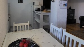 A compact living space with a dining table, chairs, a microwave, a small TV, and a ceiling fan. - Apartment Marinera (Senj)